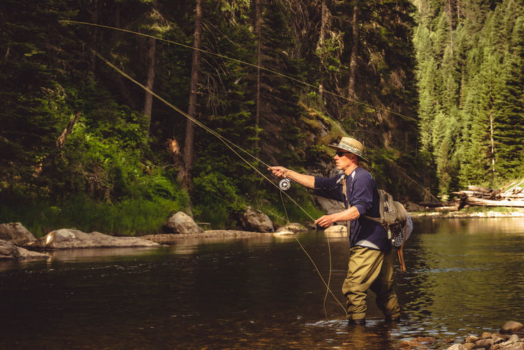 Side view of man wearing hat fishing in river