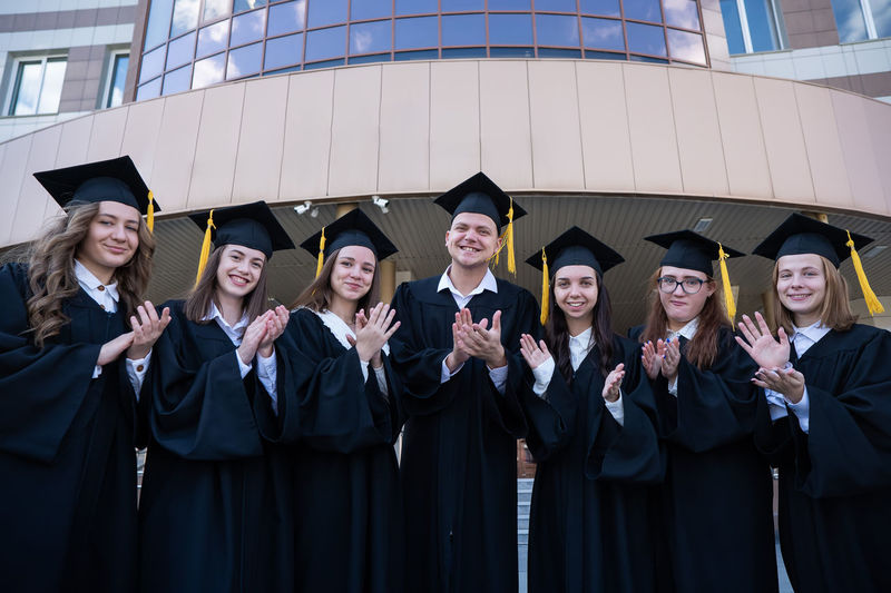 Portrait of smiling friends wearing graduation gown