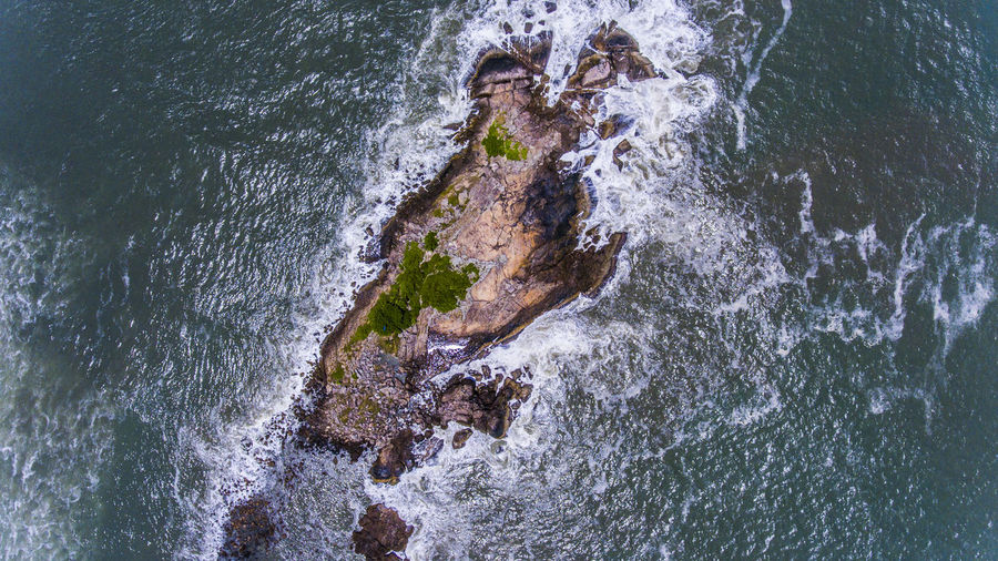 High angle view of waves splashing on rocks. island situated in guaruja, são paulo, brazil. 