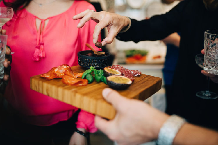 Cropped hand of man serving food to friends in party at home