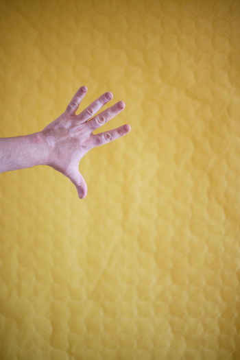 Close-up of hand on yellow wall
