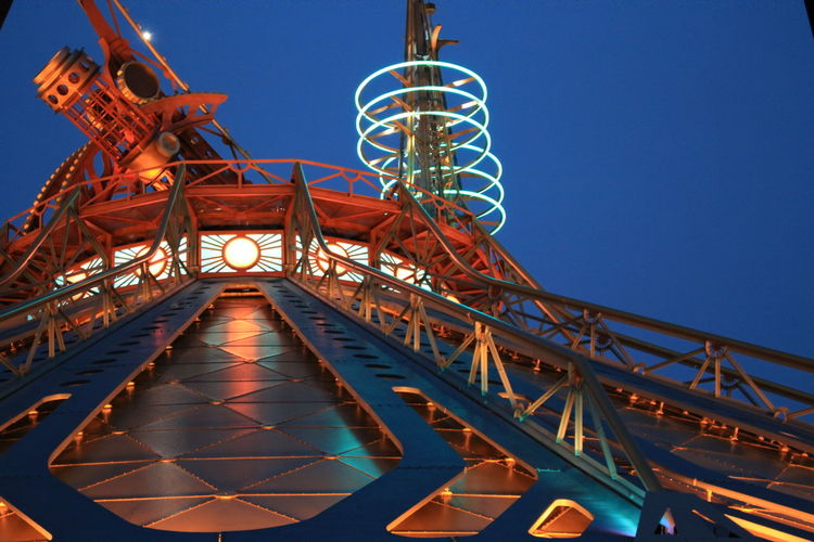 Low angle view of illuminated roller coaster against blue sky