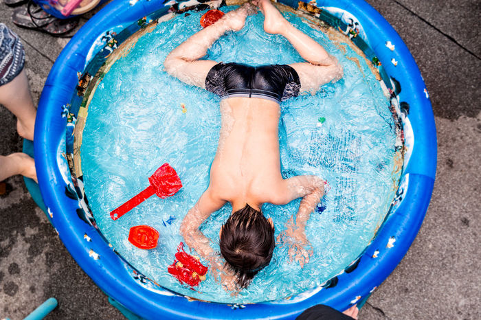 High angle view of shirtless boy playing in children pool