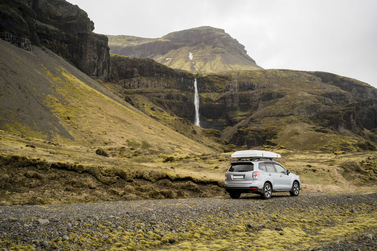 Car parked on land against mountain range
