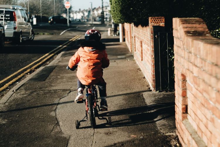 Rear view of boy riding bicycle on city