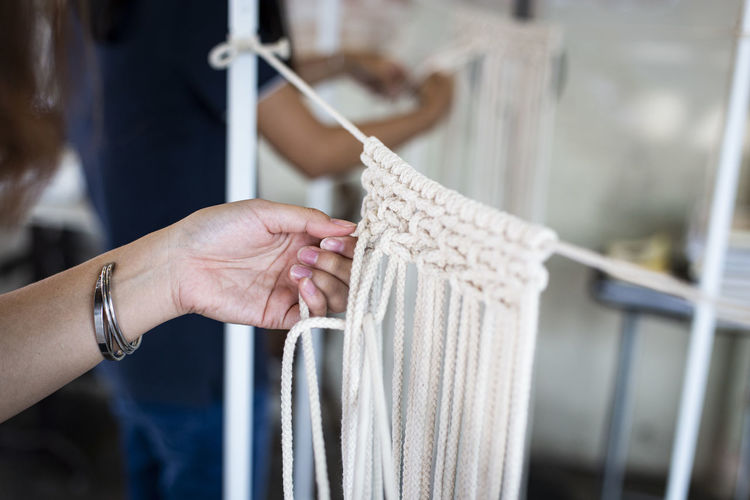 Cropped hand of woman doing macrame