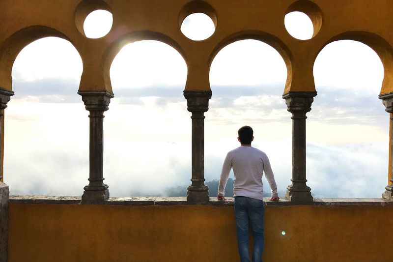 Rear view of man looking at clouds from palace at sintra