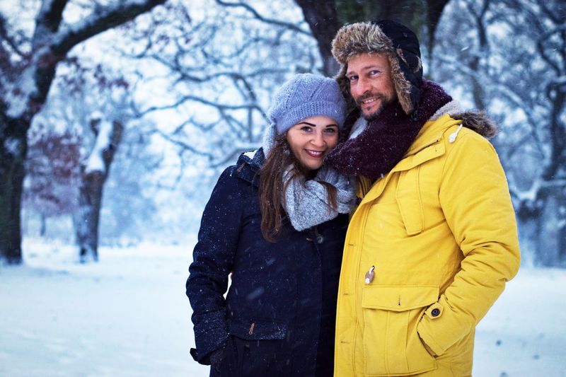 Portrait of smiling people standing on snowy field