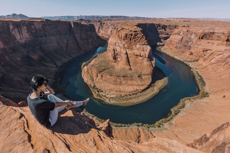Rear view of man sitting on rock