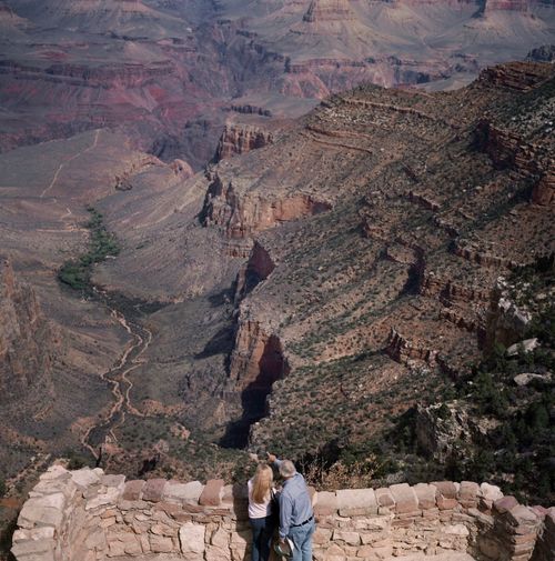 Men and women standing by stone wall and pointing at rocky mountains