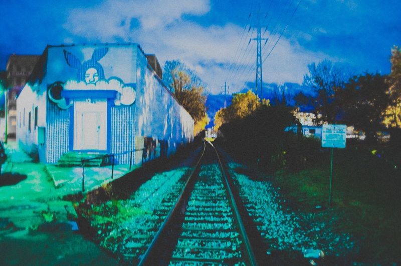 Digital composite image of railroad tracks amidst buildings against sky