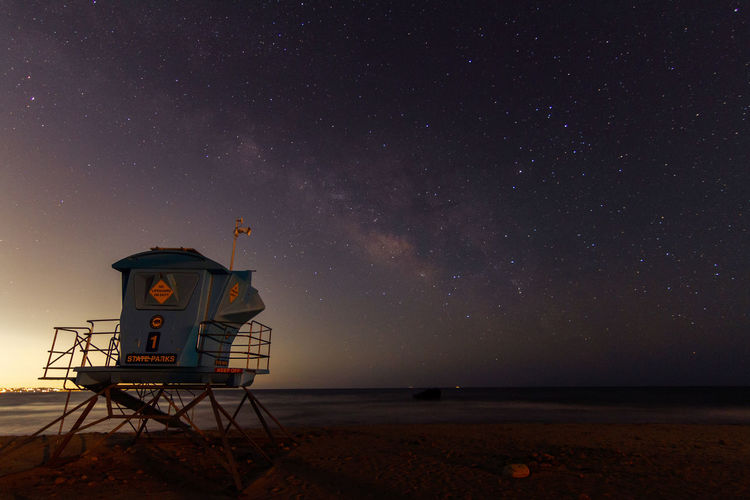 Lifeguard hut on beach against sky at night