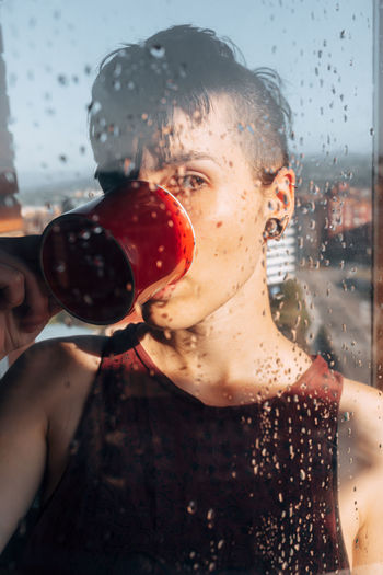 Thoughtful woman drinking coffee near window