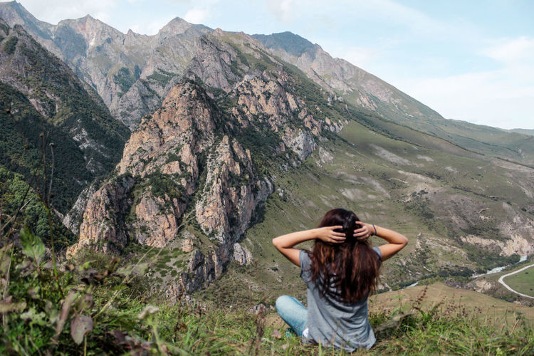 Rear view of woman sitting against mountains