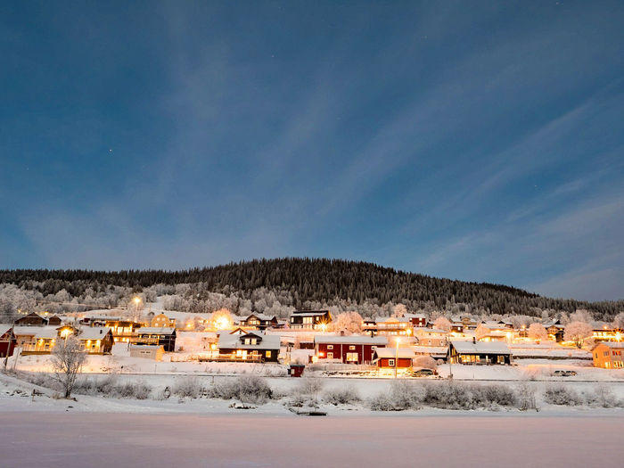 Snow covered houses in town against sky during winter