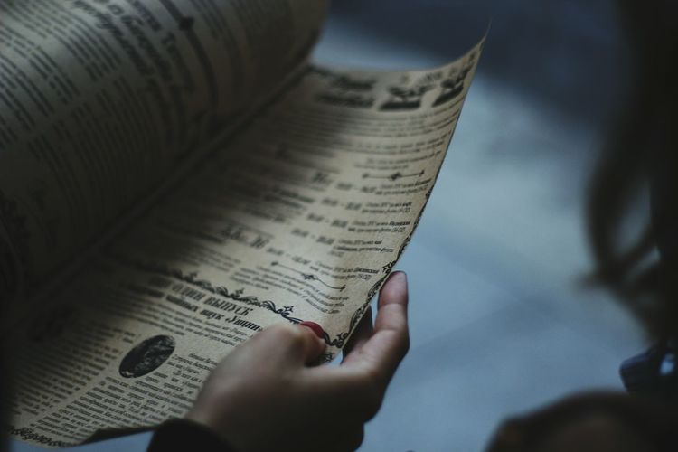 Cropped hand of woman reading newspaper