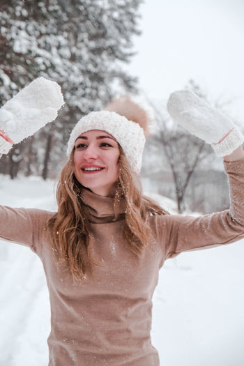 Christmas, holidays and season concept. young happy woman blowing snow in the winter forest nature