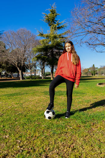 Full length of young woman playing soccer on field