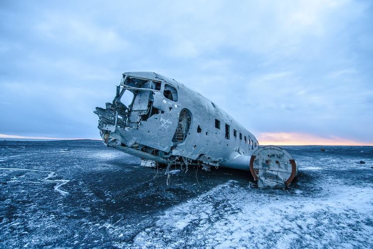 Abandoned plane on sea against sky during winter