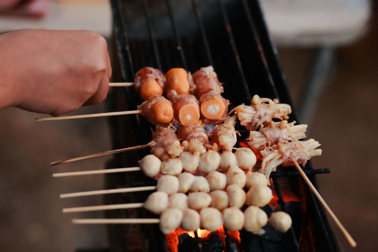 Hand holding meat on barbecue grill