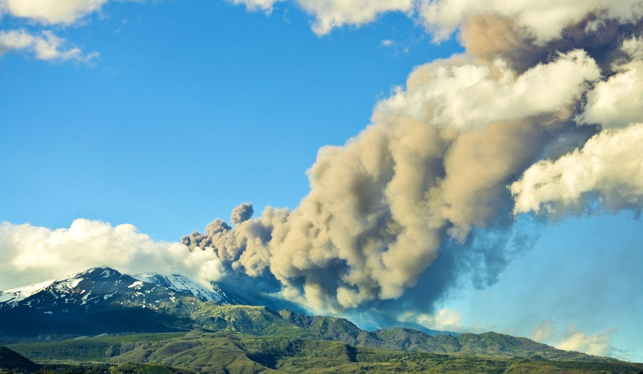 Low angle view of smoke emitting from volcanic mountain against sky