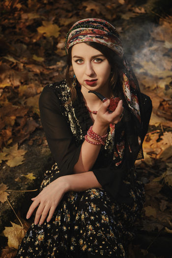 Portrait of beautiful young woman smoking while sitting outdoors
