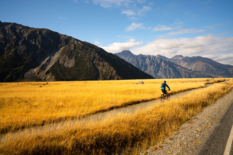 Man riding bicycle on road amidst field