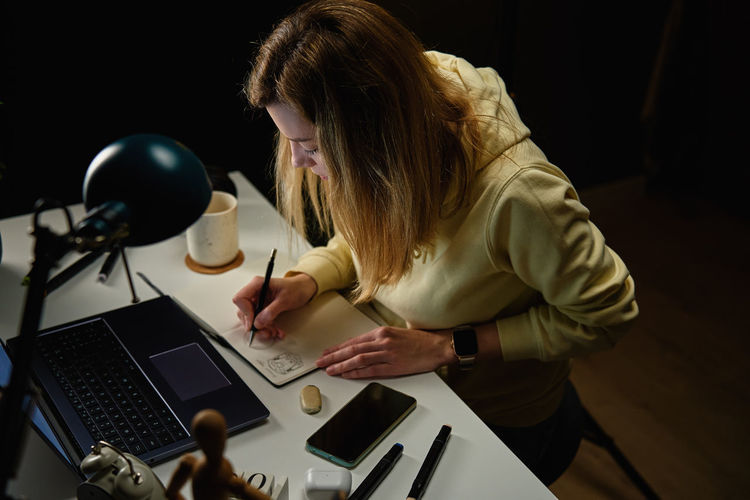 Female designer working in home office at night