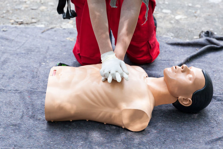 Midsection of man with cpr dummy during training