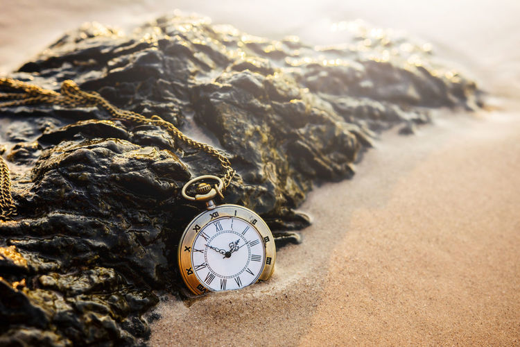 Close-up of clock pendant on sand