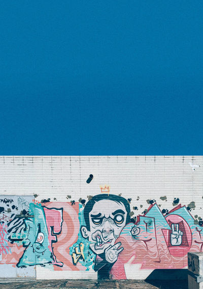 Graffiti on wall against blue sky