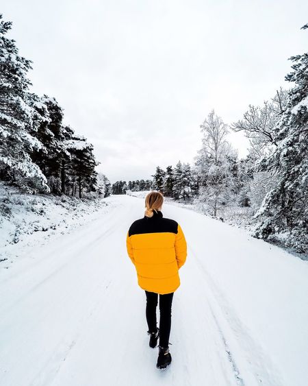 Rear view of man standing on snow covered road