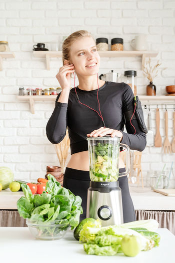Young woman listening music while preparing food in kitchen at home