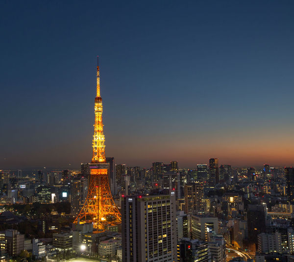 Illuminated tokyo tower and city against clear sky at dusk