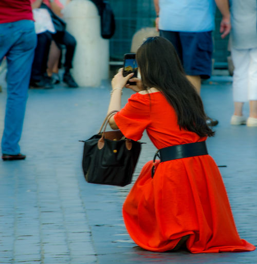Rear view of woman using mobile phone in city
