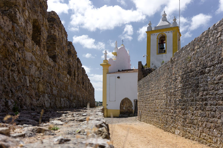 Panoramic view of cross amidst buildings against sky