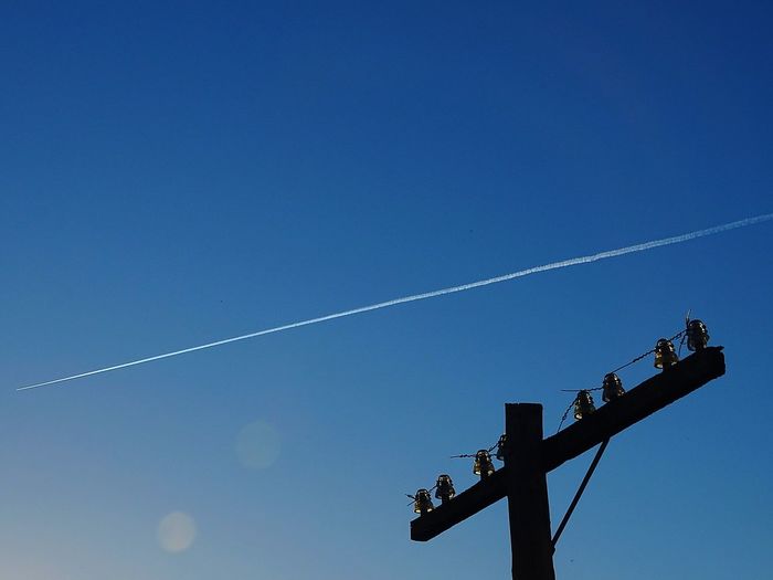 Low angle view of silhouette windmill against blue sky