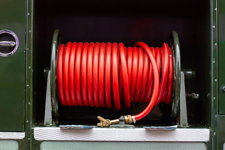  coiled or rolled red rubber fire hose seen on an old green goddess