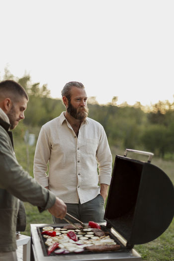 Male friends preparing food on barbecue
