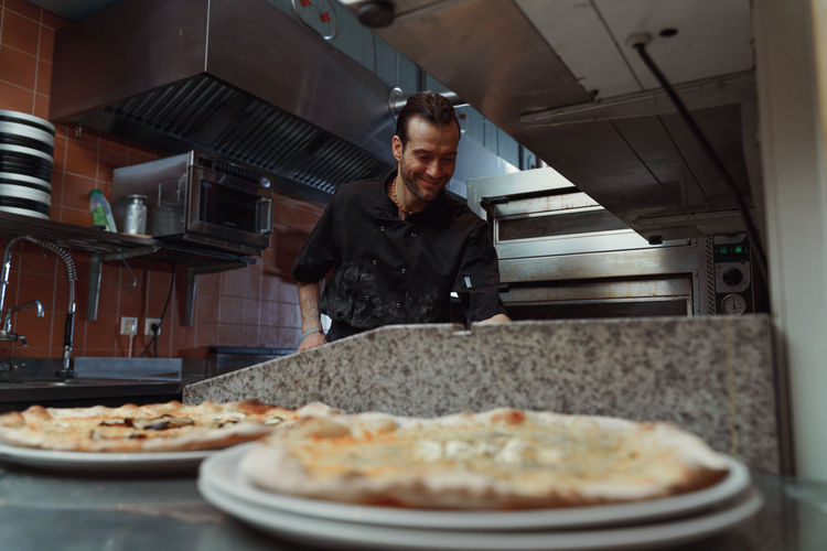 Pizza making process. male chef making authentic pizza in the pizzeria kitchen.