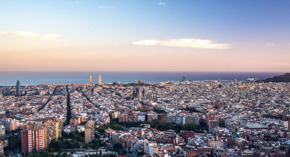 High angle view of illuminated cityscape by sea against sky