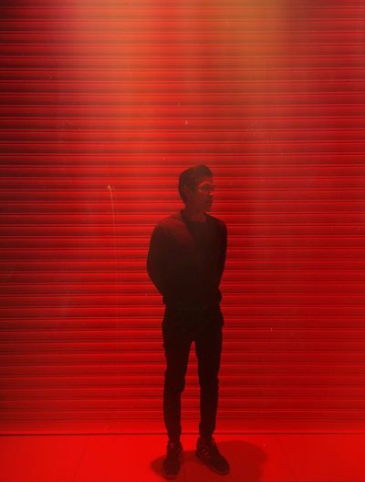 Full length of man standing against red light at night