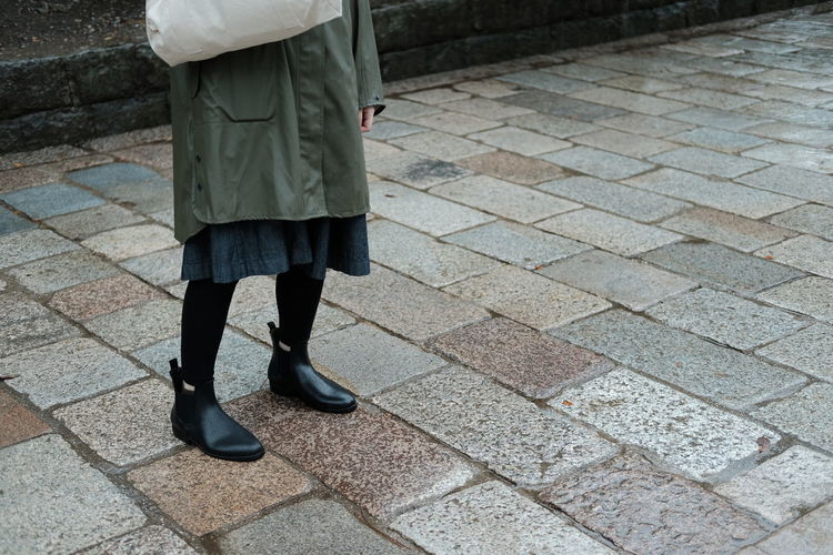 Low section of woman walking on cobblestone