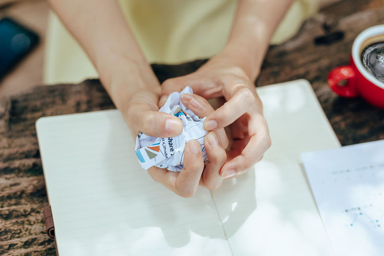 Midsection of woman holding paper with text on white table