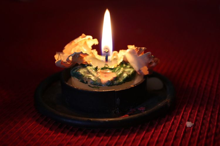 Melted lit candle on holder at table