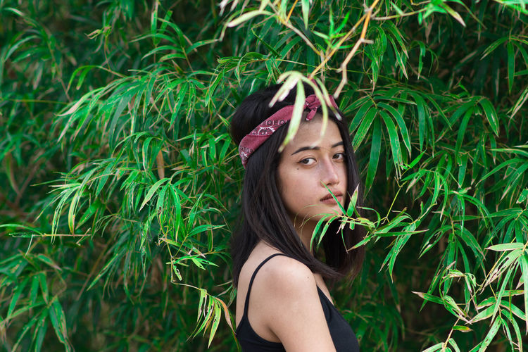 Side view portrait of young woman by plants