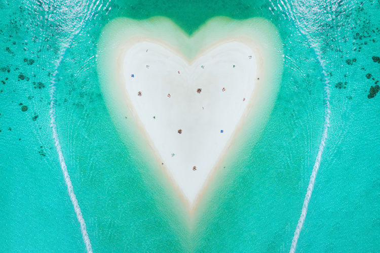 Aerial view of heart shape beach amidst sea