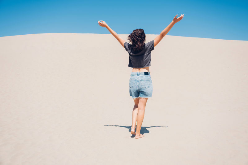 Minimalistic landscape photo of young woman walking in desert. freedom and happiness concert. 