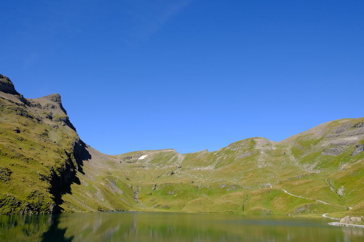 Scenic view of lake and mountains against clear blue sky