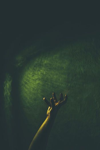 Cropped hand against green wall